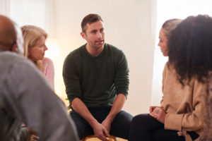 a man has made the right choice between inpatient rehab and outpatient rehab and is now getting the addiction recovery support he needs in group therapy